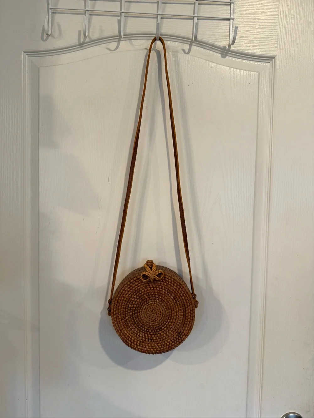 Tan, round, handwoven rattan crossbody bag